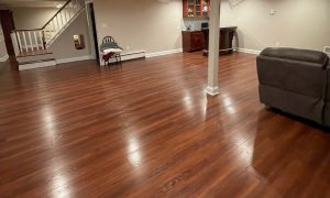 updated basement with new redish wood panel flooring that matches the cabinetry with beige walls and white details