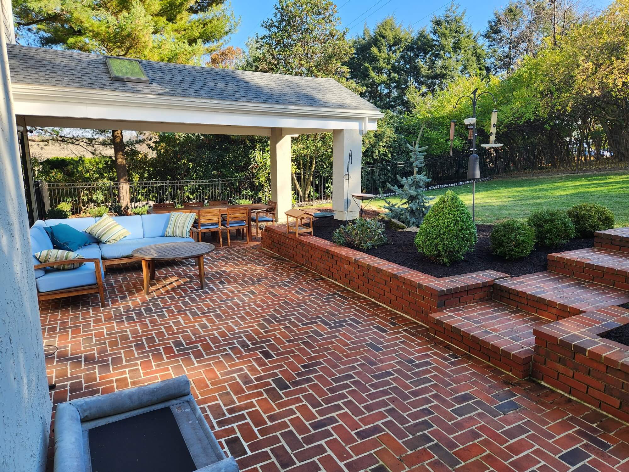 large backyard patio made of uniform bright red bricks with matching retaining walls and steps