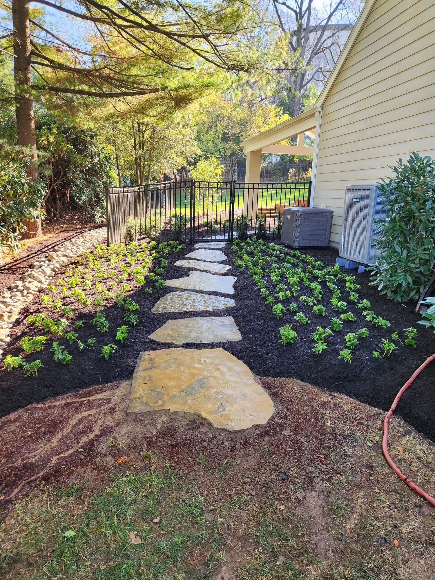natural stone pathway wrapping around a house from the backyard patio to the front