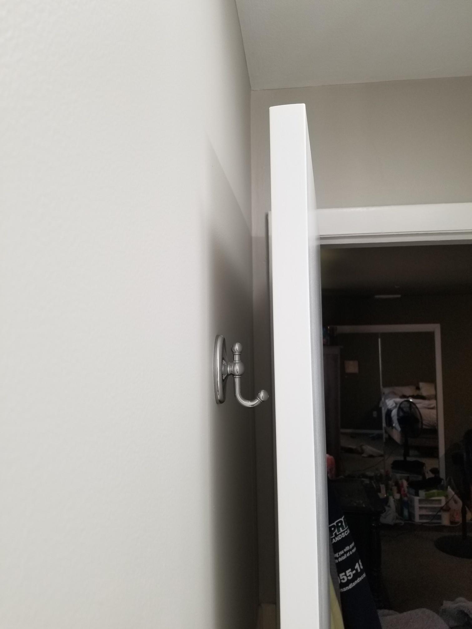 Silver robe hook on a white door, showcasing simple, functional design for hanging clothing or towels