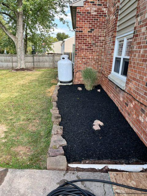 mulched flower bed next to the house by the back patio