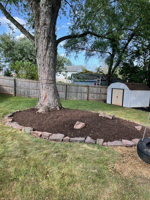 modest flower. bed with mulch around a tall tree