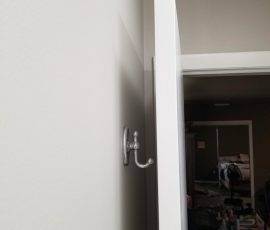 Silver robe hook on a white door, showcasing simple, functional design for hanging clothing or towels