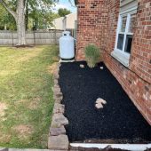 mulched flower bed next to the house by the back patio