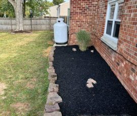mulched flower bed next to the house by the back patio