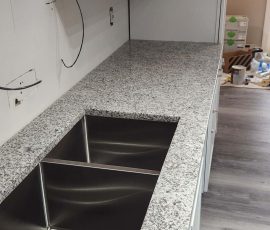 closeup on the progress of installing marble countertops around the sink